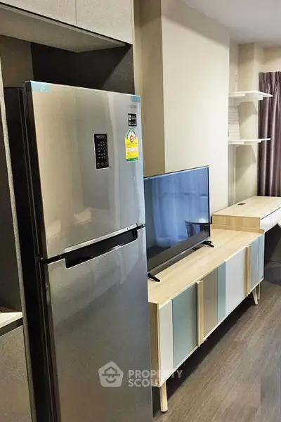 Modern living room with sleek fridge and stylish TV stand in contemporary apartment.