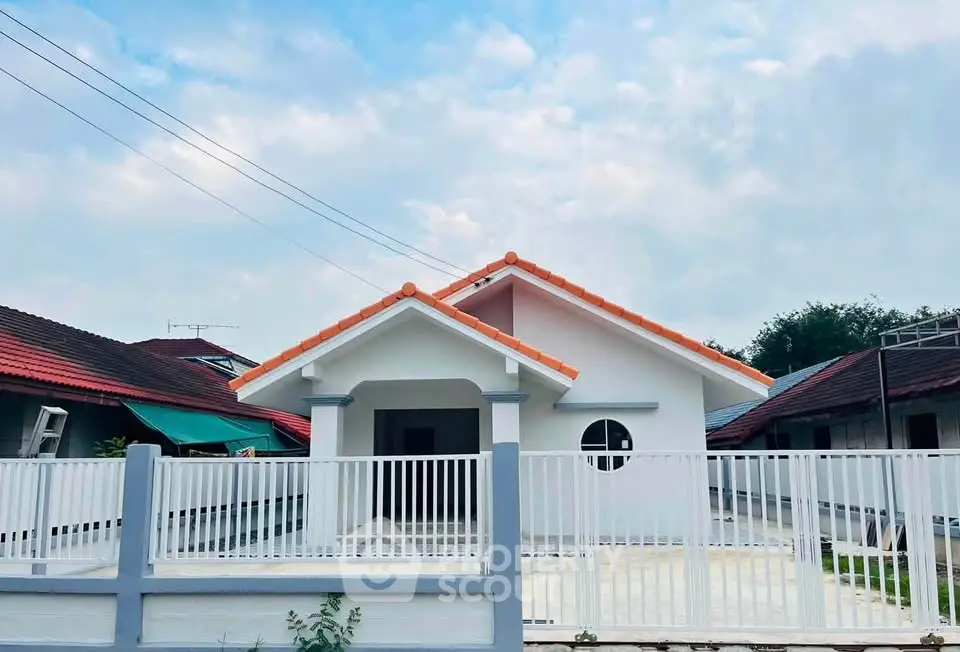Charming single-story house with red-tiled roof and white fence, perfect for family living.