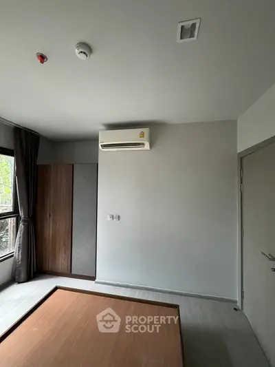 Modern bedroom with air conditioning and large window, featuring minimalist design and natural light.