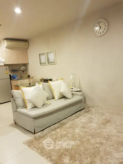Cozy living room with modern sofa and kitchen area, perfect for urban living.