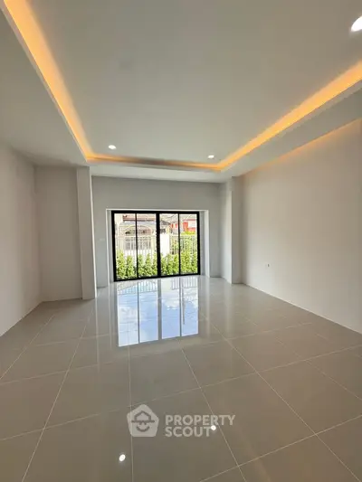 Spacious modern living room with large windows and elegant lighting.