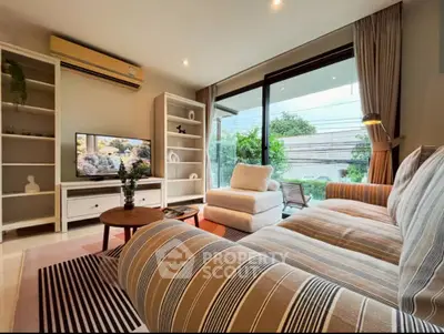 Spacious living room with modern decor and large windows offering garden view.
