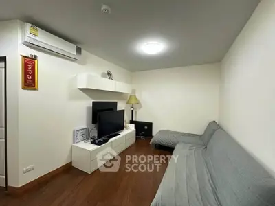 Modern living room with sleek furniture and wooden flooring, featuring a cozy sofa and entertainment setup.