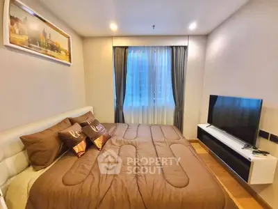 Cozy bedroom with modern decor and large TV, perfect for relaxation and entertainment.
