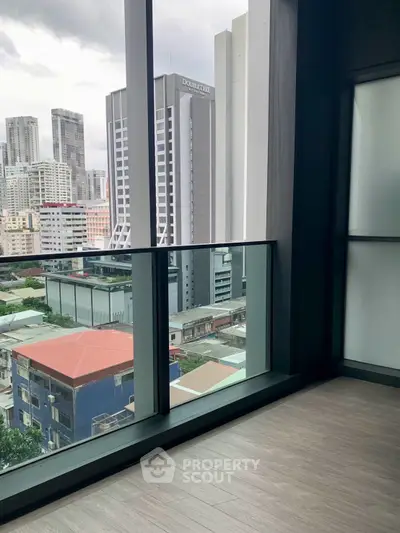 Modern high-rise balcony with cityscape view, featuring sleek glass railing and urban skyline.