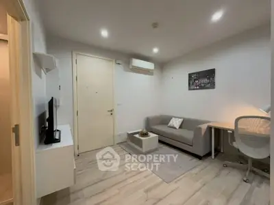 Modern living room with sleek furniture and neutral tones, featuring a cozy sofa and stylish decor.