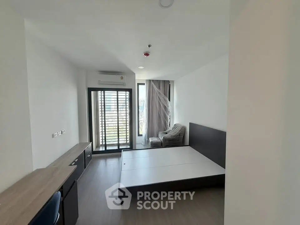 Modern bedroom with large window and balcony access in a stylish apartment.