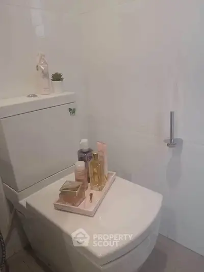 Modern bathroom with sleek white toilet and stylish decor accents.