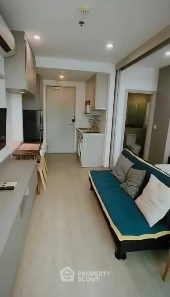 Modern compact living room with stylish furniture and open kitchen layout in a cozy apartment.