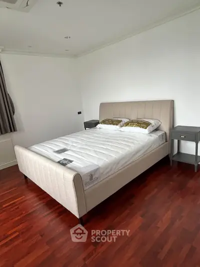 Spacious bedroom with elegant bed and hardwood flooring in modern apartment.