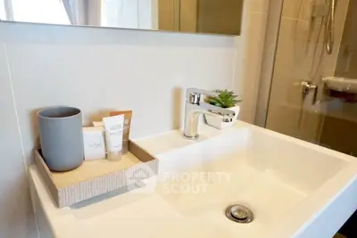 Modern bathroom sink with stylish faucet and toiletries in a contemporary setting.