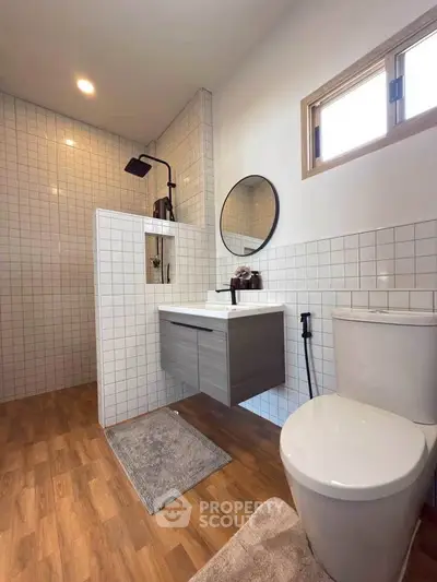 Modern bathroom with sleek fixtures and wood flooring, featuring a stylish shower area.