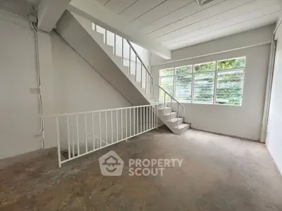 Spacious interior with staircase and large windows offering natural light, ideal for modern living.