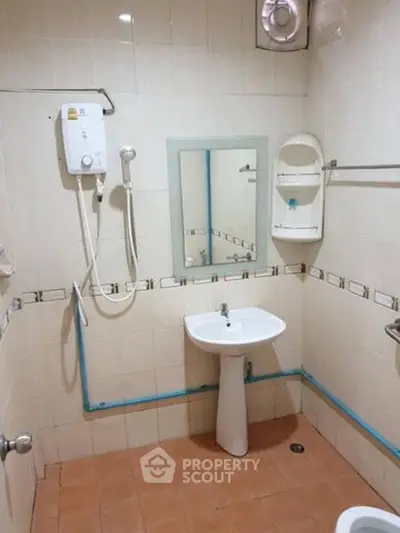 Compact bathroom with shower and pedestal sink in tiled interior