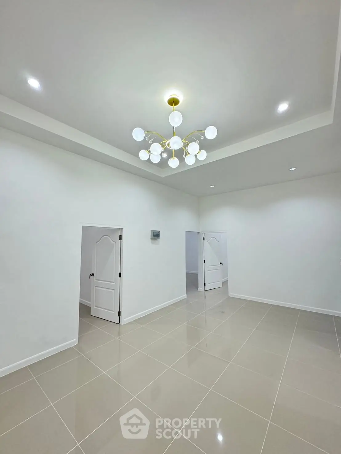 Spacious modern living room with elegant chandelier and glossy tiled flooring.