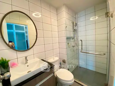 Modern bathroom with glass shower and sleek vanity in contemporary apartment.