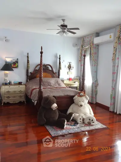 Charming bedroom with polished wooden floors, elegant drapes, and cozy teddy bears for a warm ambiance.