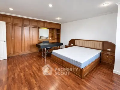 Spacious bedroom with wooden flooring and built-in wardrobe, featuring a modern bed and dressing table.