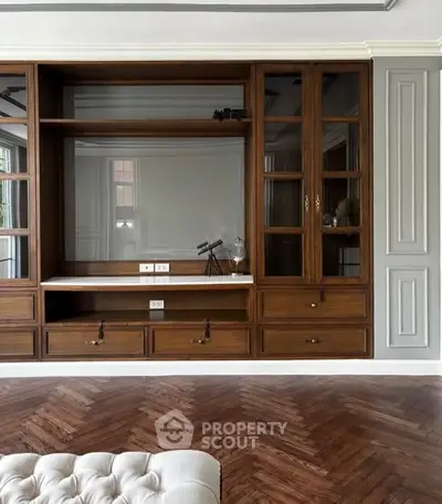 Elegant living room with built-in wooden shelves and herringbone parquet flooring.