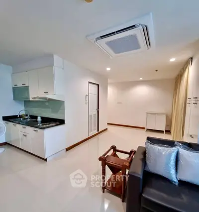 Modern open-layout living room with sleek kitchen and cozy seating area.