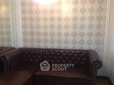 Elegant brown leather sofa in a stylish living room with patterned wallpaper.