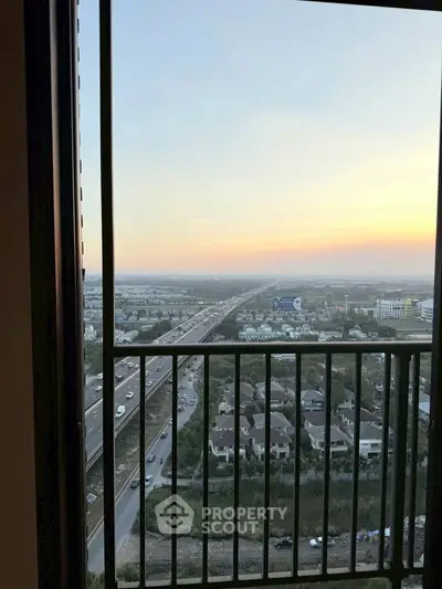 Stunning high-rise balcony view overlooking cityscape and highway at sunset.