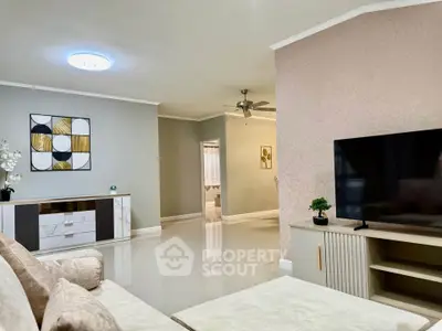 Spacious living room with modern decor and large TV, perfect for relaxation.