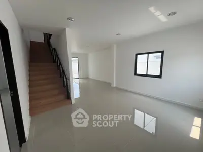 Spacious modern living room with staircase and large window, ideal for family gatherings.