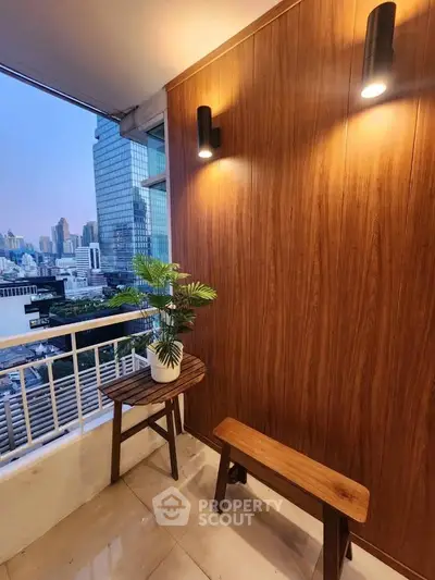 Stylish balcony with city view, featuring wooden furniture and modern lighting.