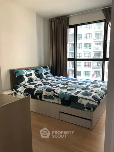 Modern bedroom with large window and stylish bedding in urban apartment