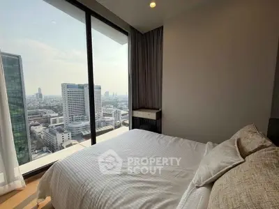 Luxurious bedroom with stunning city view from floor-to-ceiling windows in modern high-rise apartment.
