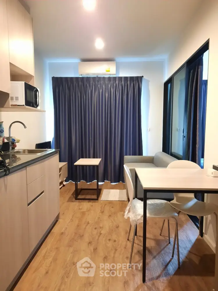 Modern compact kitchen and dining area with wooden flooring and natural light