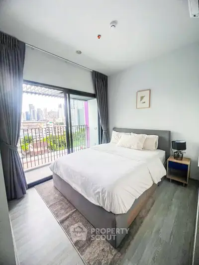 Modern bedroom with city view and balcony access in a high-rise apartment.