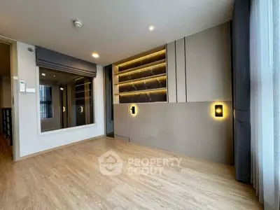 Modern living room with elegant lighting and wooden flooring, featuring a large mirror and stylish wall design.