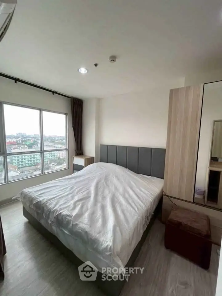 Modern bedroom with large window and city view, featuring stylish decor and ample natural light.