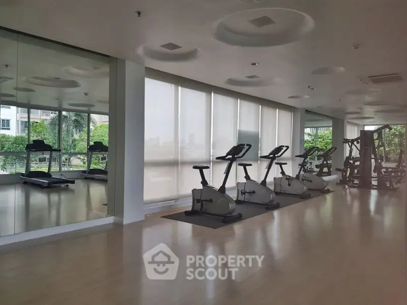 Spacious gym with modern exercise equipment and large windows offering a scenic view.