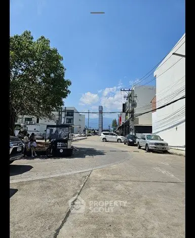 Street view with modern buildings and clear blue sky, showcasing urban development potential.