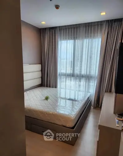 Modern bedroom with large window and stylish decor in a high-rise apartment.