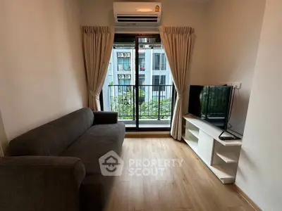 Cozy living room with modern sofa, TV, and balcony view in urban apartment.