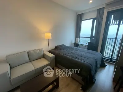 Modern bedroom with city view, featuring a cozy bed, sofa, and floor lamp, perfect for urban living.