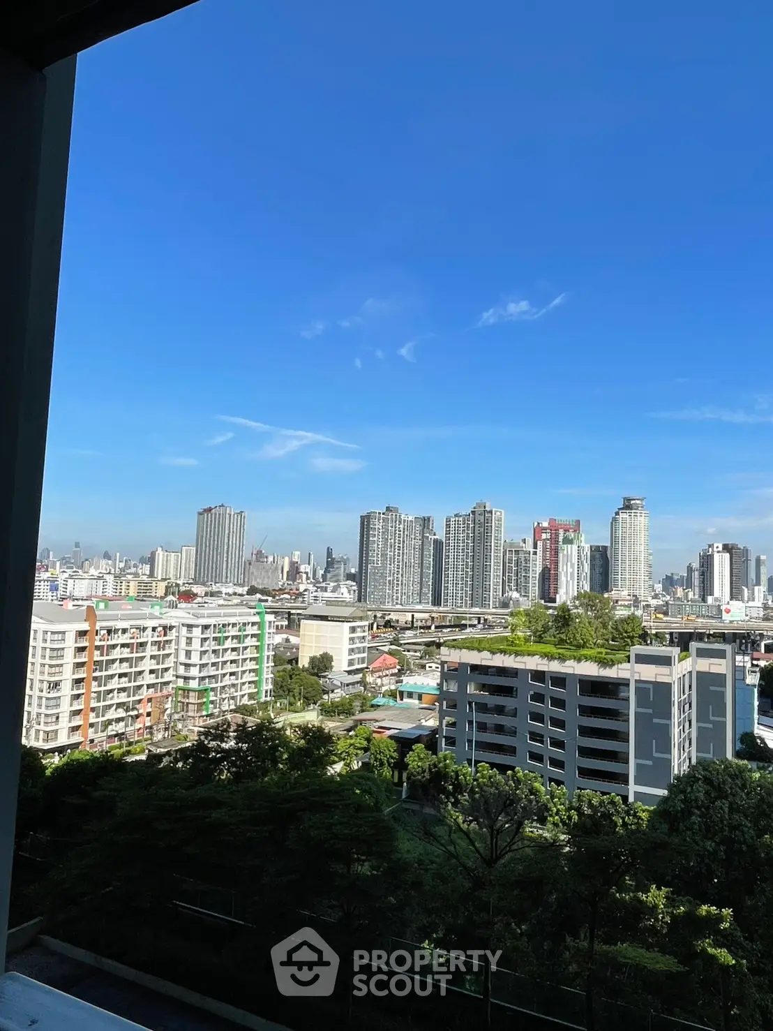 Stunning cityscape view from a high-rise apartment balcony, showcasing urban skyline and lush greenery.