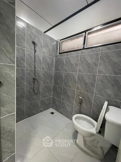 Modern bathroom with sleek gray tiles and walk-in shower design.