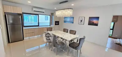 Modern dining area with elegant chandelier and open kitchen layout, featuring sleek appliances and stylish decor.