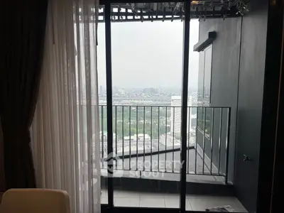 Stunning cityscape view from modern apartment balcony with glass doors.