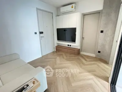 Modern living room with sleek TV setup and stylish herringbone flooring.