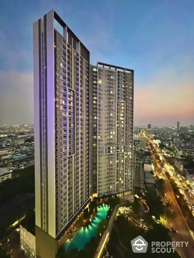 Stunning high-rise building with illuminated pool and panoramic city view at dusk.