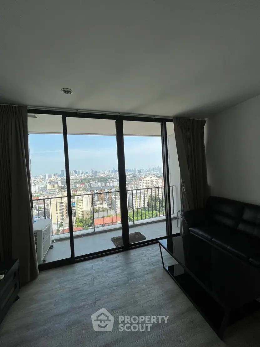 Modern living room with stunning city view from large glass doors and balcony.