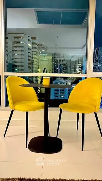 Stylish modern dining area with city view, featuring yellow chairs and sleek table.