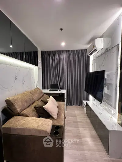 Modern living room with sleek design, featuring a plush sofa, large TV, and elegant marble accents.