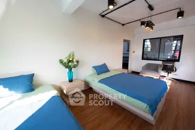 Modern bedroom with twin beds, stylish lighting, and wooden flooring for a cozy ambiance.